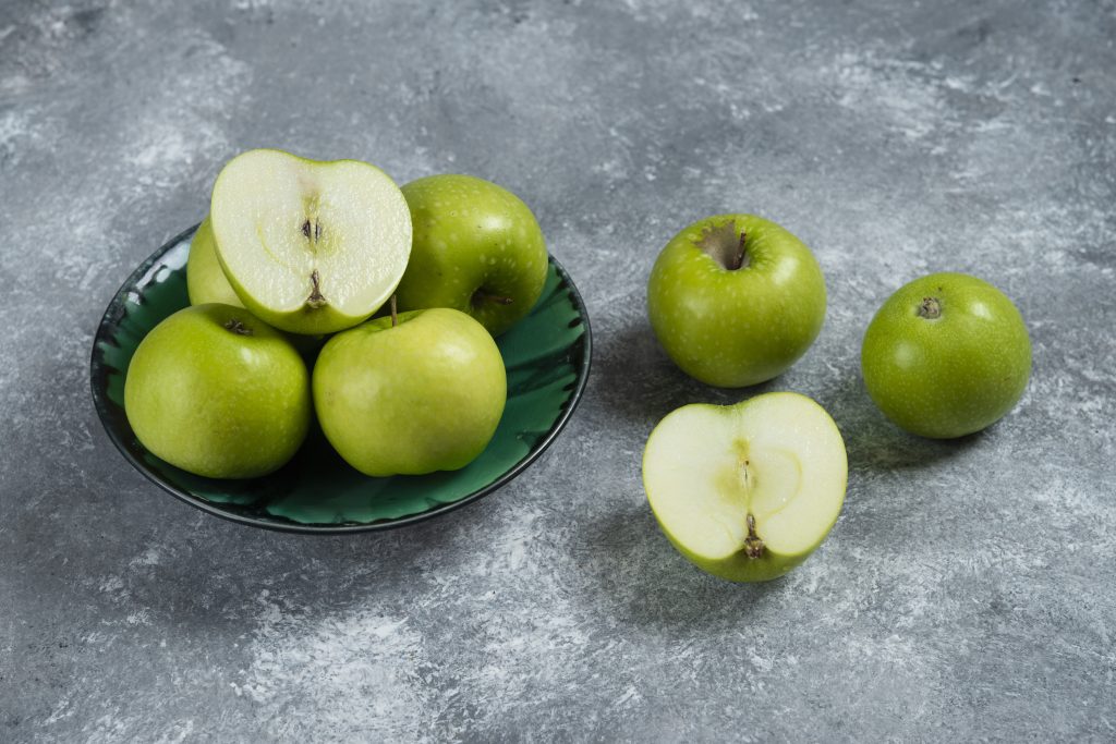 Close-up of Granny Smith apples in green bowl cut in half to show freshness