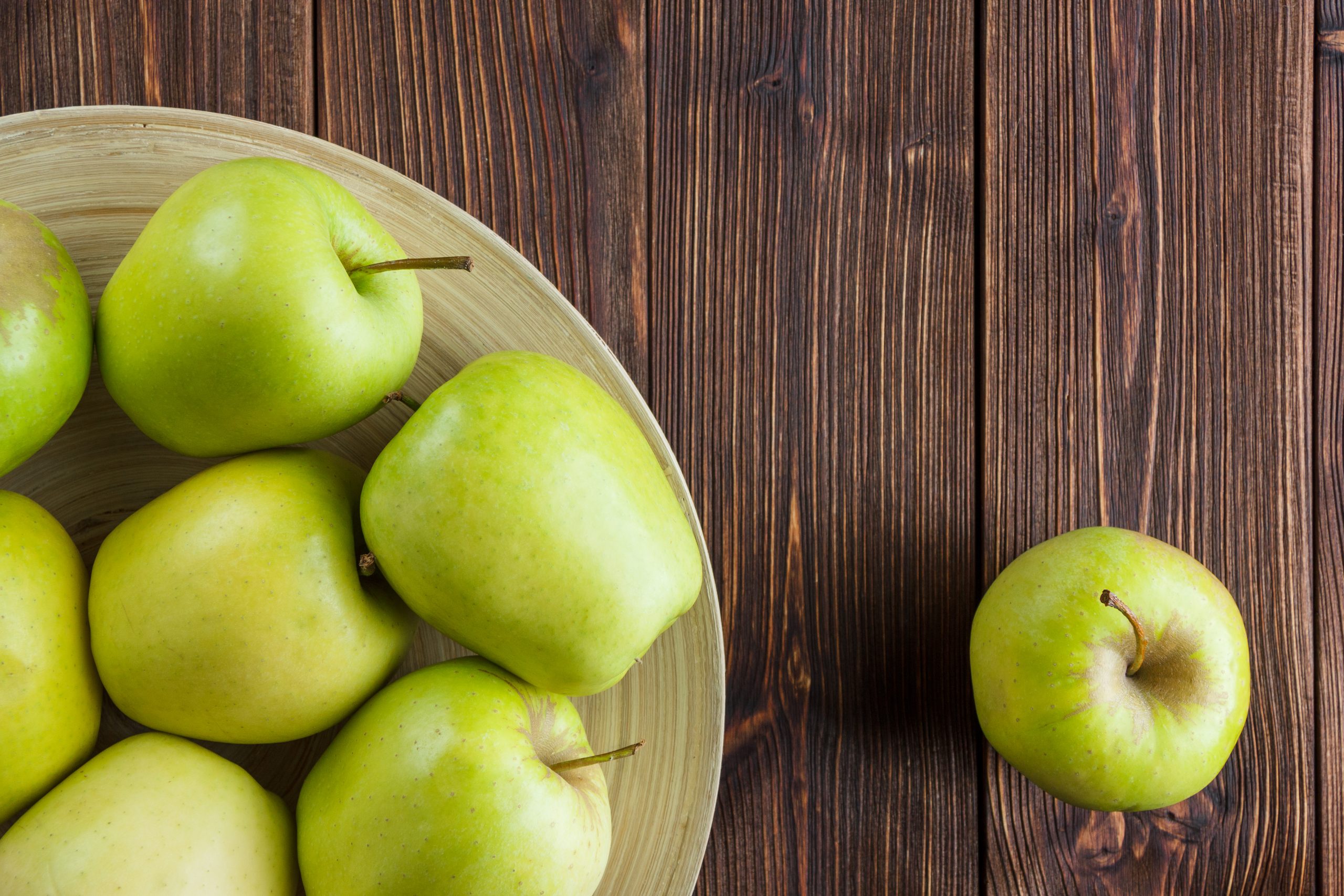 green apples plate-around top view wooden background showing bright green skin