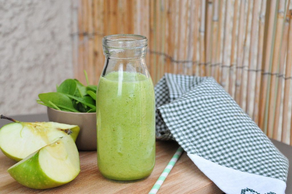 Green apple with juice on the wooden table