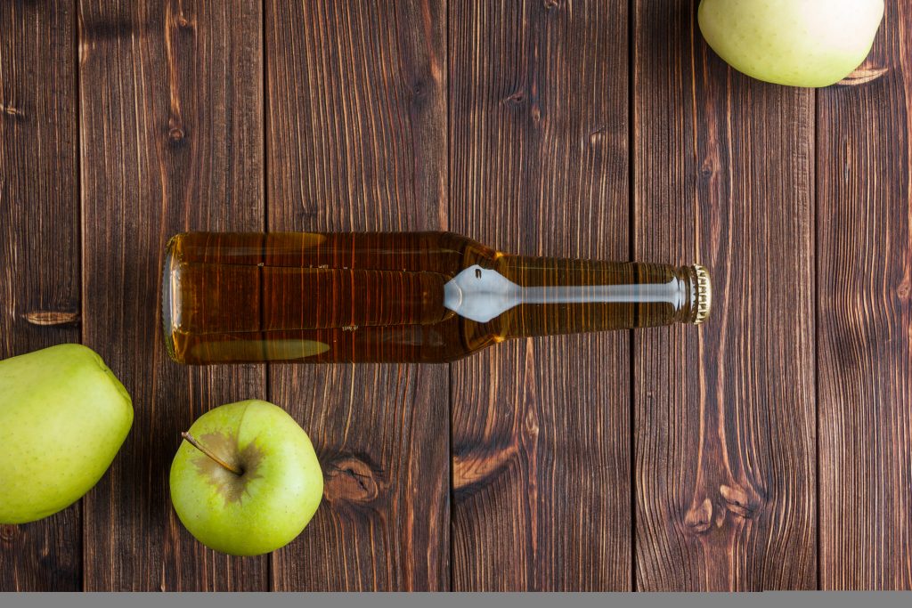 Flat lay green apples with apple cider vinegar on a wooden background