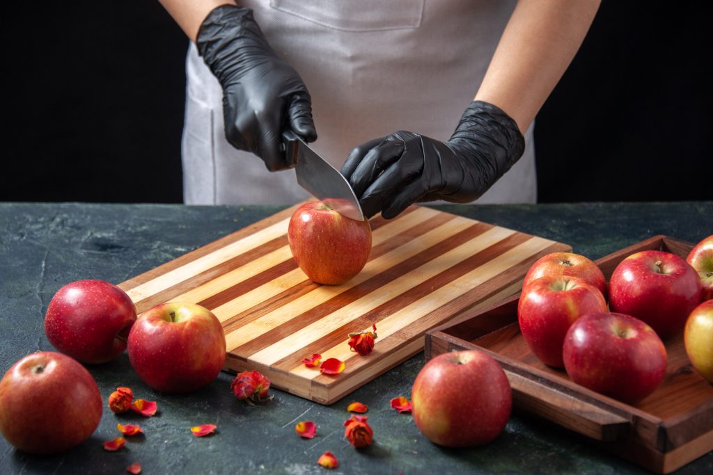 A fresh red apple on a wooden cutting board with a paring knife, ready to be cored.