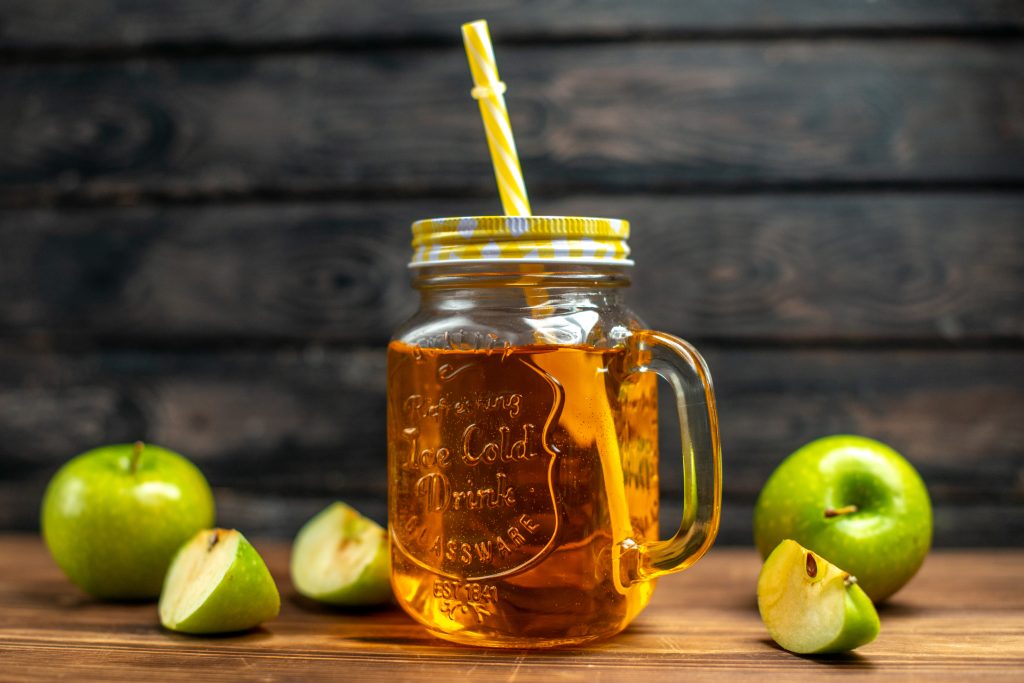 Fresh apple juice inside can with fresh apple slices near it