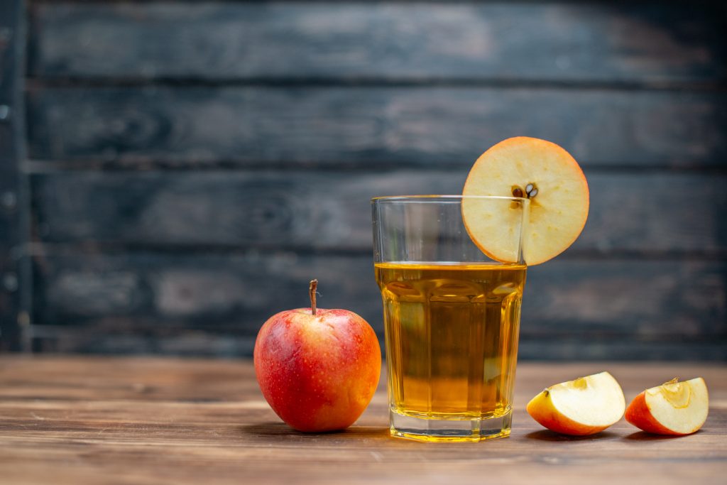 Fresh apple cider glass with apples on a wooden table
