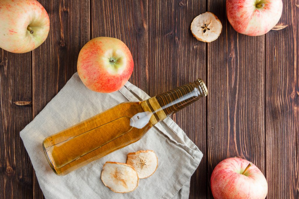 A jar of apple cider surrounded by red apples, highlighting freshness and storage tips.