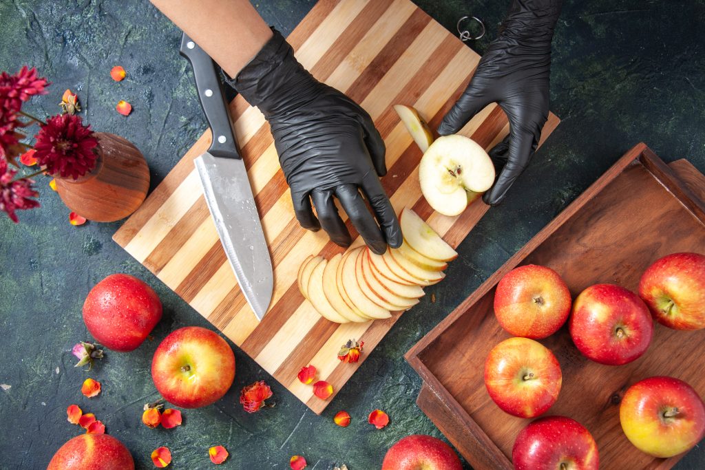 A person using a paring knife instead of a corer to remove apple seeds.