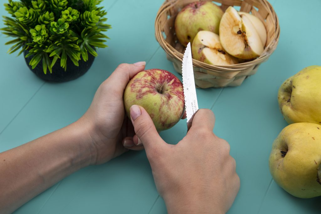 A whole apple is cutting with a sharp paring knife for coring preparation to describe, How to Core an Apple