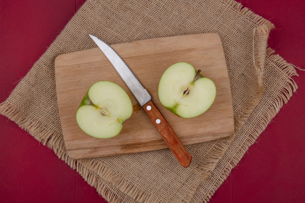 half cut apple with knife on cutting board for coring