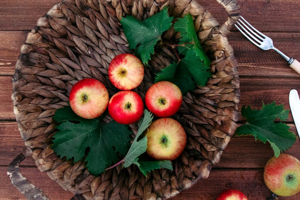 top view red apples in a wicker basket with leaves